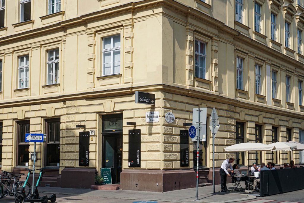 Gelbes Hauseck mit Tür und Café Goldegg Schild